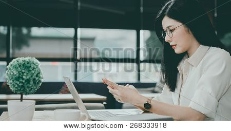 Asian Girl Is Freelancer Woman, She Is Working By Using The Laptop Computer And Driking A Cup Of Cof