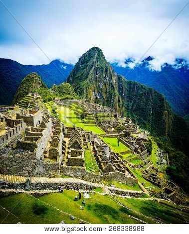 Breathtaking sunshine landscape of ancient majestic Machupicchu city among high rocky mountains under the clouds