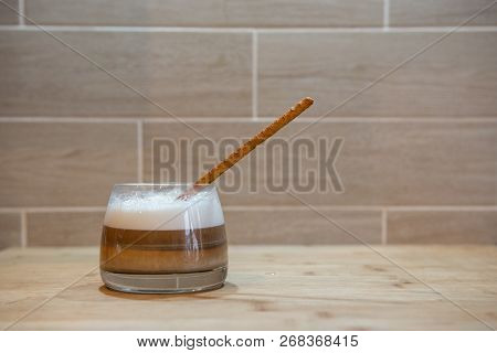 Multilayer Coffee Or Cappuccino In A Glass Cup With Bread Straw