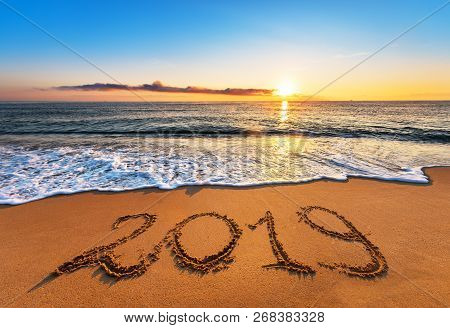 Number 2019 Written On Seashore Sand At Sunrise.
Happy New Year 2019 Concept.