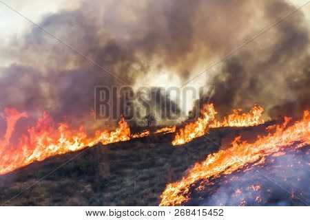 Landscape On Fire With Bright Orange Flames And Black Smoke With A Heart Shape Created In The Smoke 