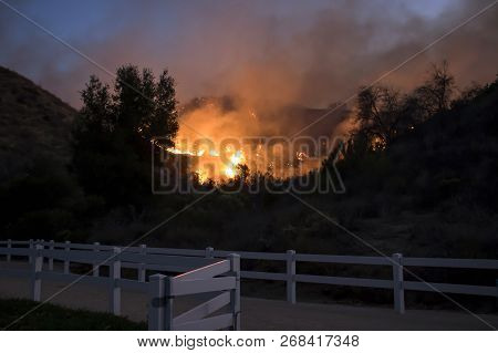 California Fire Burns Hillside Behind Suburban Neighborhood Park With Fence In Foreground.