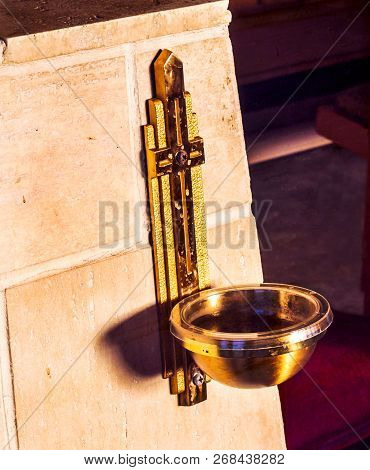 Holy Cross Brass Metal Water Bowl Attached To The Wall Of The Entry Of A Catholic Church. Holy Water