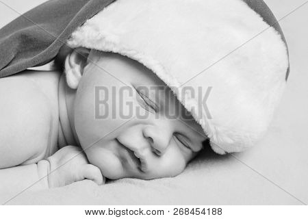 A Naked Newborn Baby Sleeps In A Christmas Hat.
