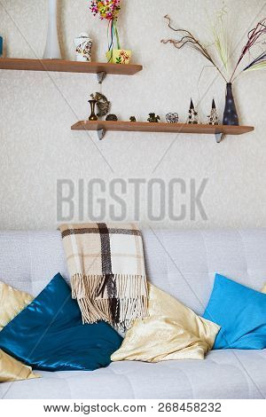 The Interior Of The Room With A Sofa And Pillows On It And Shelves Abouve It. Things On The Shelf