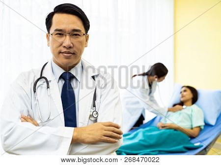 Portrait of Young adult Doctor with nurse and Patient in background.
