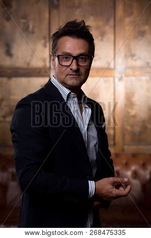 Portrait Of The Dark Haired Man Standing In The Room Alone And Looking Attentively At You
