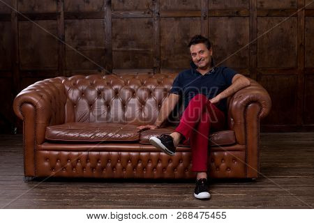 Positive Middle Aged Man Feeling Glad And Smiling While Being In The Laconic Room And Sitting On The