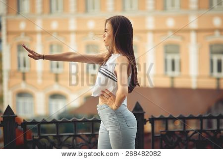 Portrait Of A Girl In Jeans And A T-shirt On The Background Of The Building In The Evening On A Summ