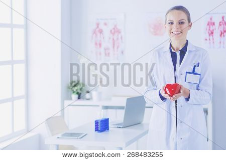 A doctor with stethoscope examining red heart, isolated on white background