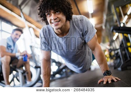 Portrait Of A Handsome Man Doing Push Ups Exercise In Gym