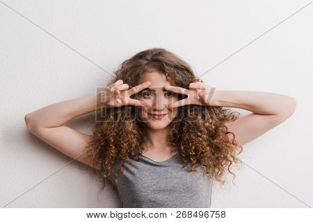 Young Beautiful Cheerful Woman In Studio, Fingers Forming V.