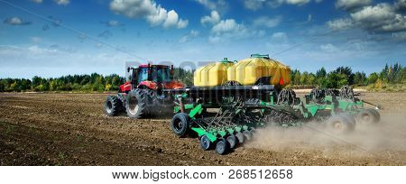  Modern, green tractor in the spring field work on the background of a beautiful rural landscape.