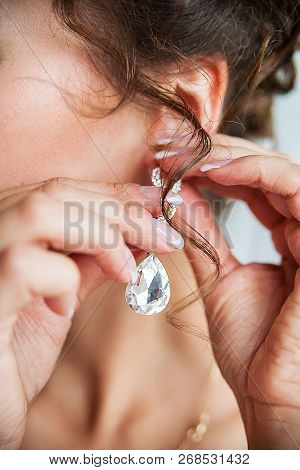Wedding Bride Hangs Gold Earrings With Diamond.
