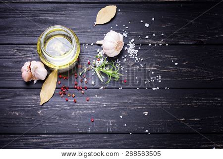 Bottle With Olive Oil With Herb And Spices Ob Black Wooden Background. Top View. Selective Focus. Pl