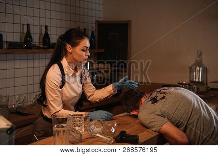 Concentarted Female Detective Investigating Dead Body At Crime Scene