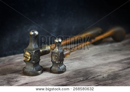 Two Old Vintage Hammers From A Goldsmith On A Wooden Workbench Against A Dark Background With Copy S