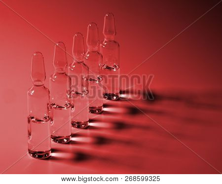 Row Of Ampulas With Medicine On Red Background, Closeup