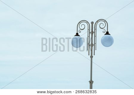 White Pillar In Vintage Style With Double Suspended Lantern In Sphere Form On Blue Sky Background. S