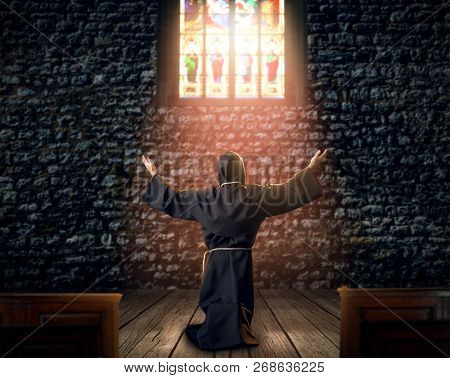 Medieval monk kneeling and praying in church
