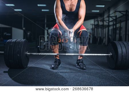 Powerlifter rubs his hands with talcum powder