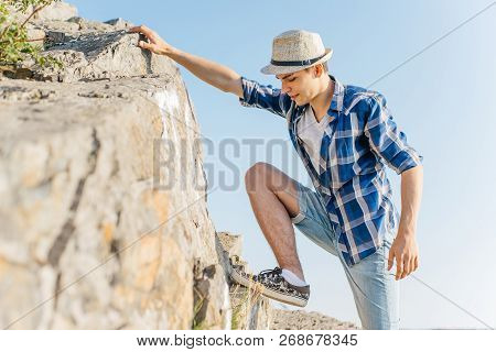 Male Hiker Climbing Up Mountain Cliff During Hiis Travel