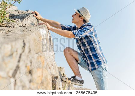 Male Hiker Climbing Up Mountain Cliff During Hiis Travel