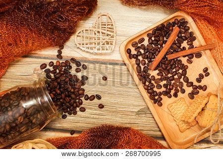 Scarf, Glass Jar, Cookies, Cinnamon Sticks And Scattered Coffee Beans On Vintage Wooden Table. Top V