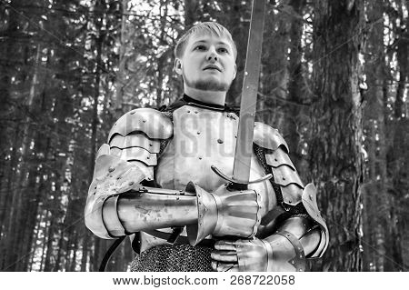 Knight In Armor And With A Sword In The Middle Of A Winter Forest. Vintage Military Uniform.