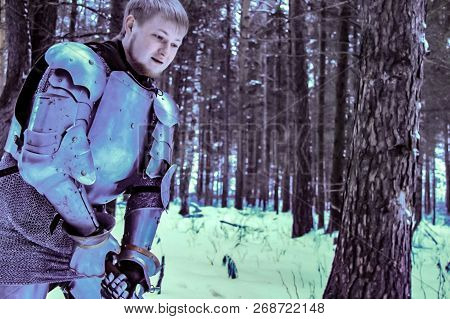 Knight In Armor And With A Sword In The Middle Of A Winter Forest. Vintage Military Uniform.