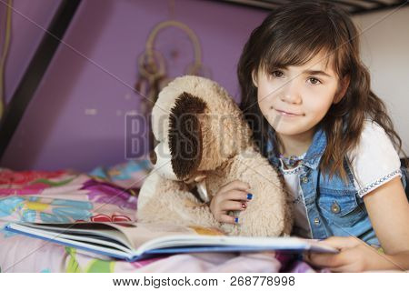7 Years Old Girl Reading A Book On Bed