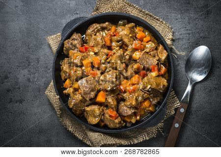 Beef Stew With Vegetables In Iron Pan On Black Background. European Cuisine. Top View.