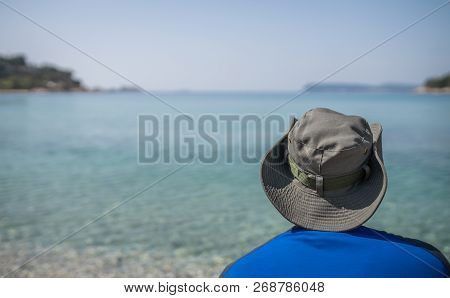 Tourist Wearing A Hat Standing On A Beach And Looking At The Stunning Croatian Coast In Dubrovnik