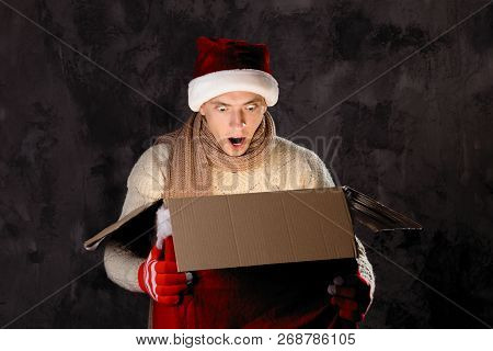 Christmas Gift Concept. Man In Santa Hat Bring Gift For You. Attractive Man Hold Box.  Christmas And