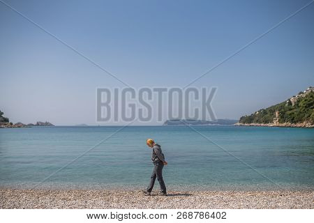 Blond Caucasian Female Tourist Walking Slowly On The Beach And Admiring The Stunning Croatian Coast 