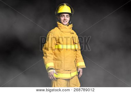 Portrait Of The Fireman Standing Waist Up Studio Shot On Black Background And Moke.