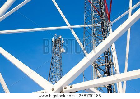 Metal Structures Of Cell Tower Against A Blue Sky. Ladder, Support Towers And Metal Construction Of 