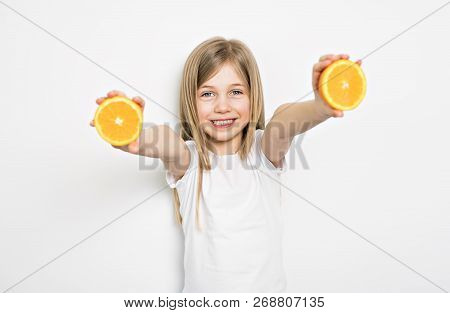 Happy Small Five Years Old Girl With Straight Hair Over White Background At Home Holding Orange
