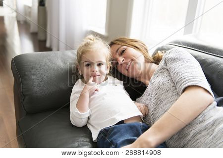 Happy Mother With Her Daughter On The Sofa In The Living Room At Home