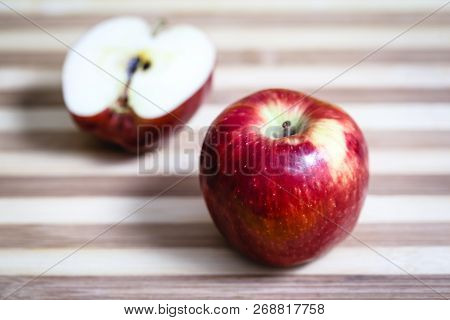 Red Apple Next To Slices Of Another Apple.