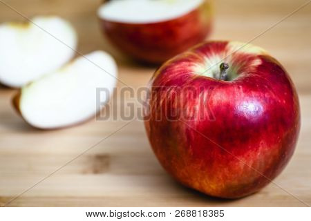 Red Apple Next To Slices Of Another Apple.