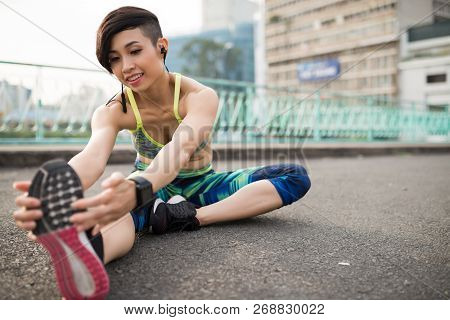 Pretty Positive Young Woman Stetching Legs Outdoor After Jogging