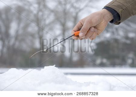Winter Fishing Concept. Hand Of Fisherman With Specialised Rod Above Snowy Ice.