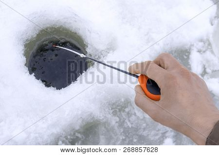 Winter Fishing Concept. Hand Of Fisherman With Specialised Rod Above Snowy Ice.