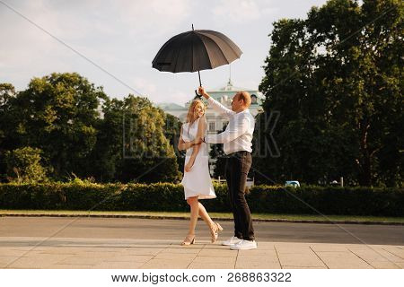 Young Couple Jump Up With Black Upbrella. Lovely Cuople Have Fun