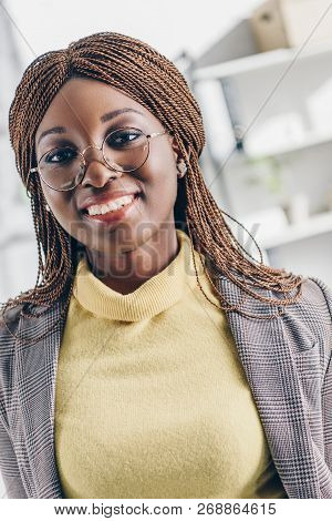 Portrait Of Smiling Stylish African American Adult Businesswoman In Formar Wear And Round Glasses