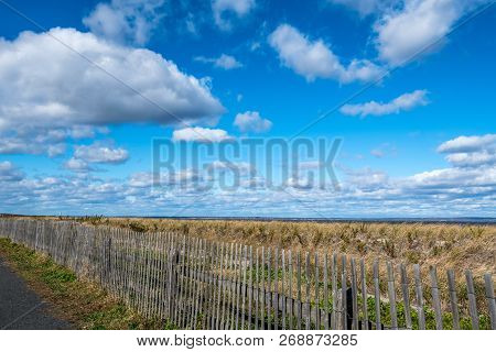 Blue Sky, Clouds And Wooden Picket Fence Along The Coastline In Bayshore Waterfront Park In Monouth 
