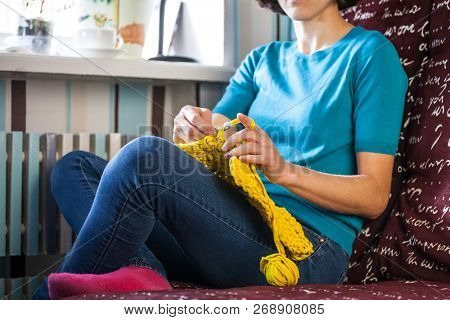 Woman Knits Crochet. The Girl Sits On The Couch And Knits From Knitting Yarn. Crochet Thick Threads.