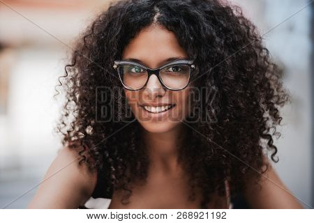 Close-up Outdoor Portrait Of A Dazzling Young Caucasian Woman With Curly Bulky Hair, Brown Eyes And 