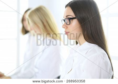Attractive Businesswoman At Meeting Or Conference Against The Background Of Colleagues. Group Of Bus